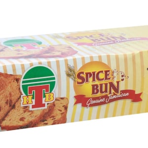 Puede incluir: Una caja de T.H.B. Spice Bun, un pastel jamaiquino. La caja es amarilla con acentos rojos y verdes. La parte delantera de la caja presenta una imagen del pan de especias y el texto "Spice Bun Genuine Jamaican". La parte posterior de la caja tiene el texto "Original Jamaican Recipe" y "Net Wt. 28 oz (794g)".