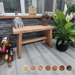 May include: A wooden bench with a natural finish and a single shelf. The bench is in a home setting with a stone wall behind it. The bench is 91 cm long and 46 cm wide.
