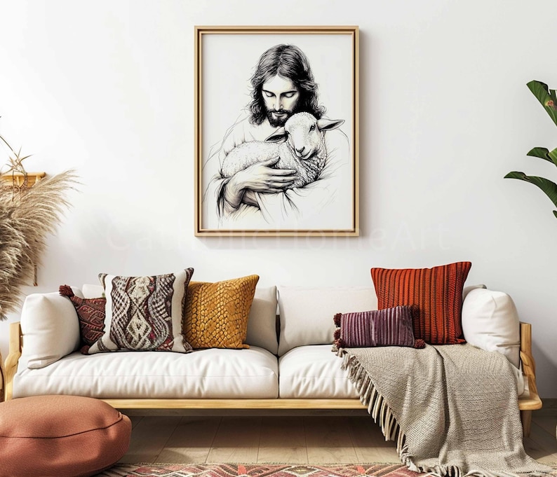 May include: A framed black and white art print depicts a figure holding a lamb. The artwork is displayed above a white sofa with decorative pillows in shades of brown, orange, and burgundy. A neutral-toned throw blanket and a floor cushion complete the scene.