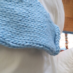 May include: A light blue knitted throw blanket with a soft, fluffy texture.