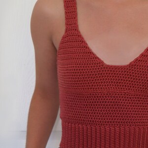 May include: A terracotta crocheted tank top with a v-neckline.