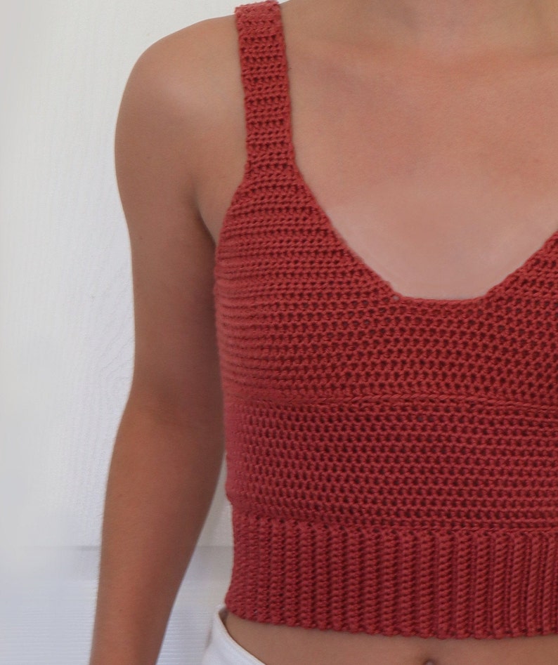 May include: A terracotta crocheted tank top with a v-neckline.