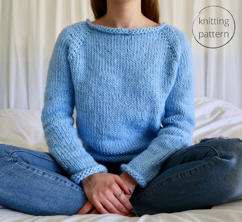 May include: A light blue knitted sweater with a round neckline and long sleeves. The sweater is made with a simple stitch pattern and has a relaxed fit.