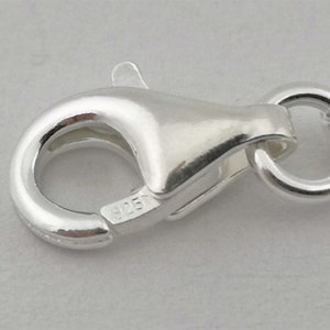 May include: Close-up of a silver lobster clasp with a 925 stamp.