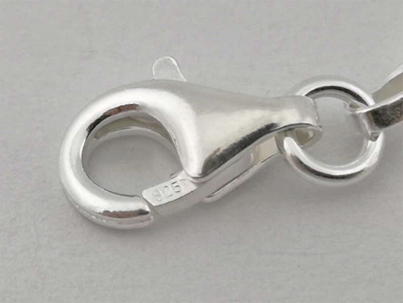 May include: Close-up of a silver lobster clasp with a 925 stamp.