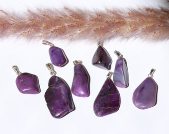 Puede incluir: Una colección de ocho colgantes de color morado y plateado hechos de piedra natural. Los colgantes son de diferentes formas y tamaños, y están dispuestos sobre un fondo blanco.