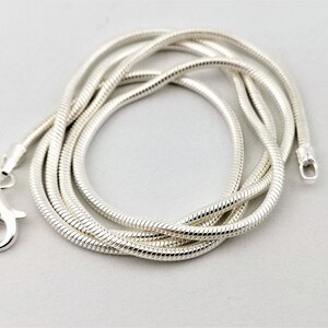 May include: A silver snake chain necklace with a lobster clasp closure.