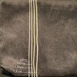 May include: Four silver snake chains of different thicknesses, laid out side-by-side on a brown surface. The chains are labeled with their thicknesses in millimeters: 1.0mm, 1.2mm, 1.4mm, and 1.6mm.