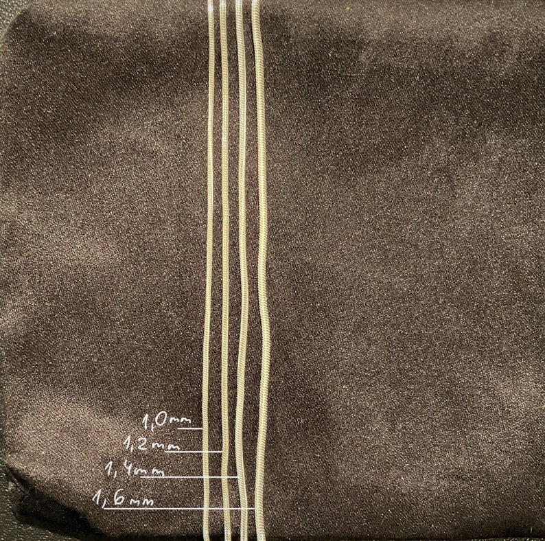May include: Four silver snake chains of different thicknesses, laid out side-by-side on a brown surface. The chains are labeled with their thicknesses in millimeters: 1.0mm, 1.2mm, 1.4mm, and 1.6mm.
