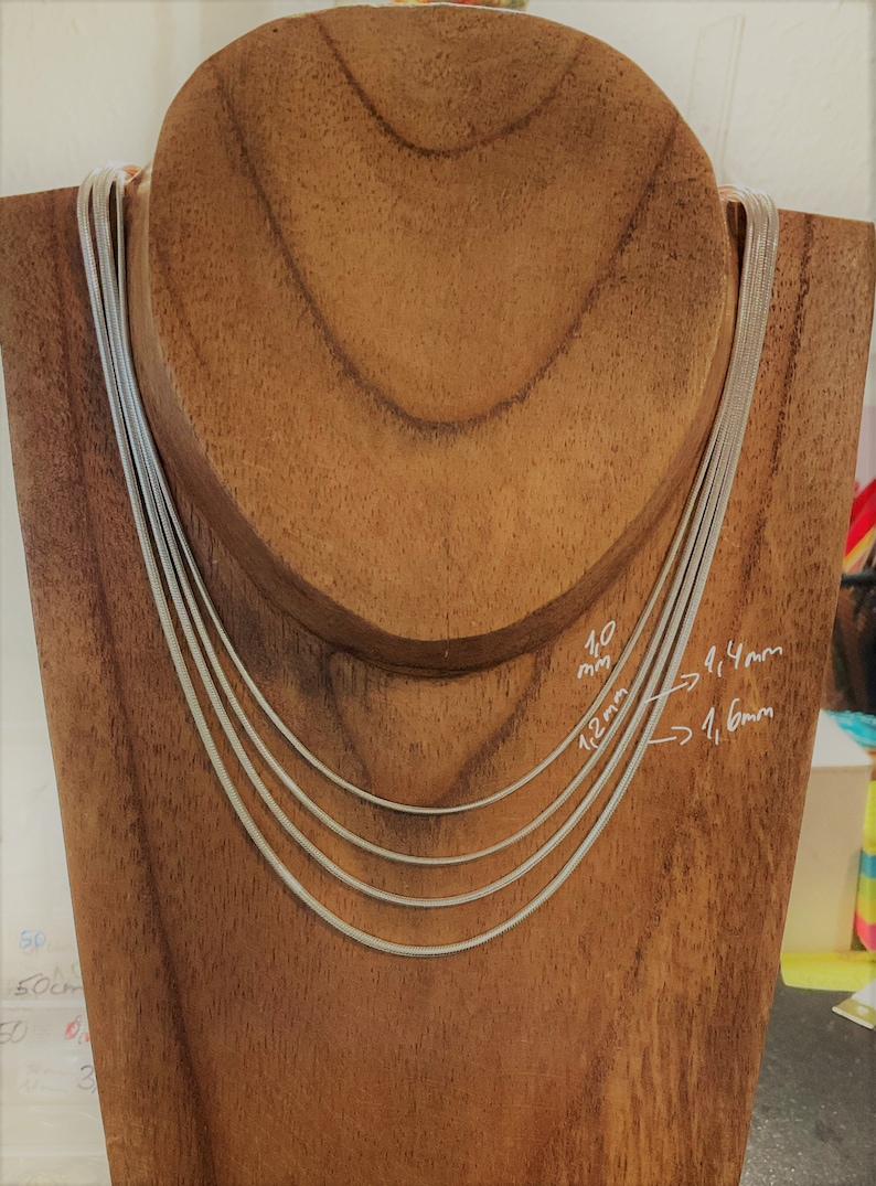 May include: Four silver snake chains of different widths displayed on a wooden mannequin. The chains are labeled with their widths in millimeters: 1.0 mm, 1.2 mm, 1.4 mm, and 1.6 mm.