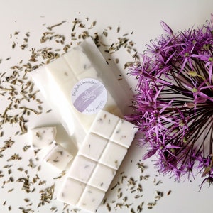 May include: A white wax melt bar with a lavender scent. The bar is divided into squares and has dried lavender flowers mixed in. The wax melt is packaged in a clear plastic bag with a white label that says "English Lavender Wax Melts".
