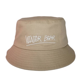 May include: A beige bucket hat with the words "Winter Bear" embroidered in white on the front.