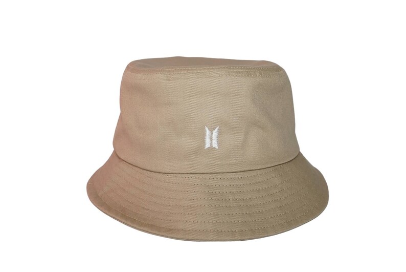 May include: A beige bucket hat with a white embroidered logo of a stylized "B" with wings.