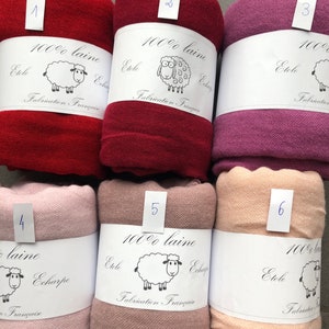 Pode incluir: Seis cachec&oacute;is de l&atilde; enrolados em v&aacute;rias cores, incluindo vermelho, bord&ocirc; e rosa. Cada cachecol &eacute; rotulado com um n&uacute;mero e uma faixa branca com uma ilustra&ccedil;&atilde;o de ovelha e o texto "100% laine, Etole, Echarpe, Fabrication Fran&ccedil;aise."