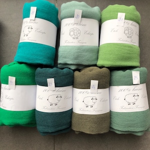 Pode incluir: Uma cole&ccedil;&atilde;o de len&ccedil;os enrolados em v&aacute;rios tons de verde, do turquesa ao azeitona. Cada len&ccedil;o &eacute; embrulhado com uma etiqueta branca com uma ilustra&ccedil;&atilde;o de ovelha e texto em franc&ecirc;s. Os len&ccedil;os s&atilde;o 100% l&atilde;.