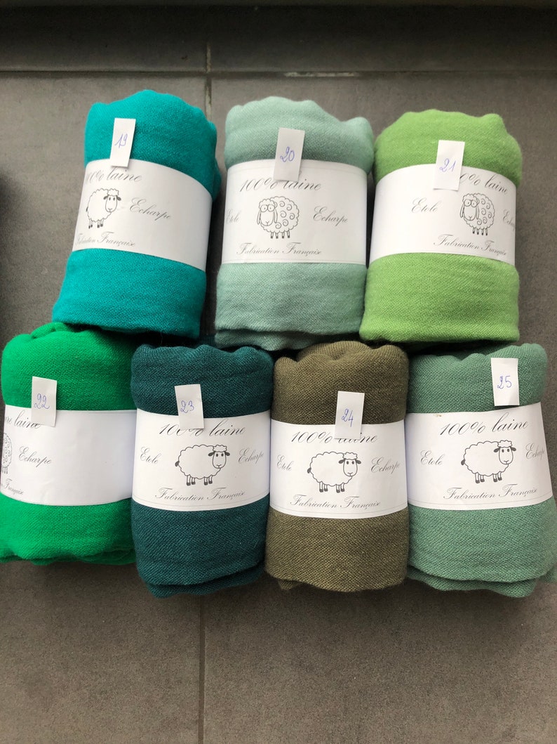 Pode incluir: Uma cole&ccedil;&atilde;o de len&ccedil;os enrolados em v&aacute;rios tons de verde, do turquesa ao azeitona. Cada len&ccedil;o &eacute; embrulhado com uma etiqueta branca com uma ilustra&ccedil;&atilde;o de ovelha e texto em franc&ecirc;s. Os len&ccedil;os s&atilde;o 100% l&atilde;.