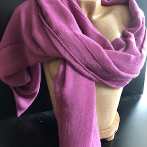 Pode incluir: Len&ccedil;o magenta drapeado sobre um manequim. O tecido do len&ccedil;o tem uma textura vis&iacute;vel e detalhes de costura. A cor &eacute; um tom rico e profundo, sugerindo um acess&oacute;rio vers&aacute;til adequado para diferentes roupas e ocasi&otilde;es.