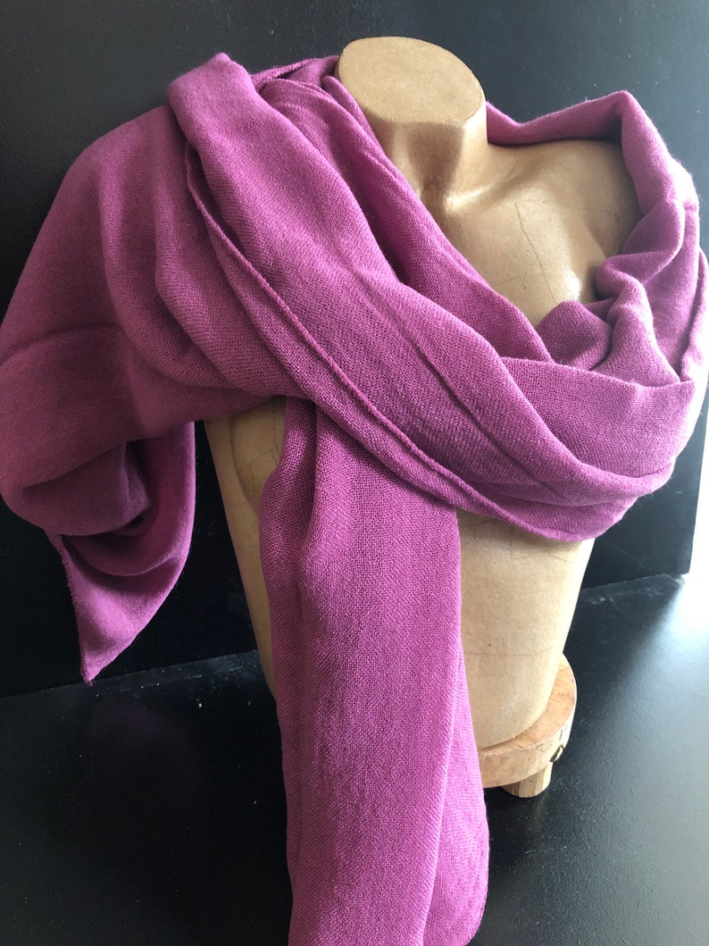 Pode incluir: Len&ccedil;o magenta drapeado sobre um manequim. O tecido do len&ccedil;o tem uma textura vis&iacute;vel e detalhes de costura. A cor &eacute; um tom rico e profundo, sugerindo um acess&oacute;rio vers&aacute;til adequado para diferentes roupas e ocasi&otilde;es.