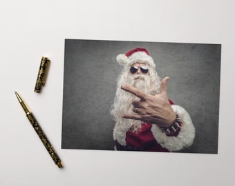 May include: A Santa Claus wearing sunglasses and a red and white suit is making a rock and roll hand gesture. He has a white beard and a red Santa hat.