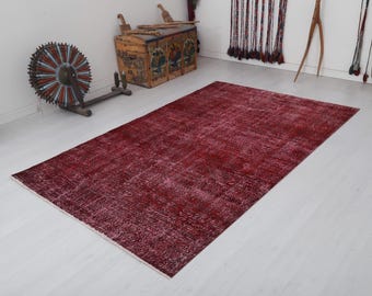 Könnte beinhalten: Ein vintagefarbener roter und weißer Teppich mit einem verblassten, abgenutzten Look. Der Teppich hat eine rechteckige Form und ist aus einem weichen, gewebten Material gefertigt.