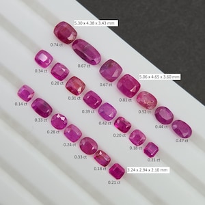 May include: A collection of various-sized, faceted, red gemstones, including rubies, displayed on a white surface. The gemstones vary in shape, from square to oval, with measurements in millimeters and carat weights. The largest stone measures 5.30 x 4.38 x 3.43 mm.