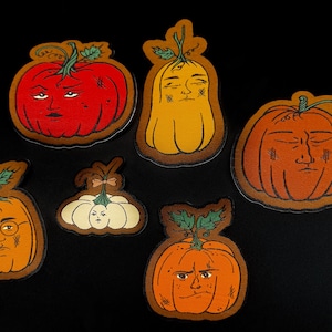May include: A collection of whimsical pumpkin-shaped stickers with expressive faces. The pumpkins are in various shades of orange, yellow, and red, with green vines and leaves. Each pumpkin has a unique facial expression, adding a touch of personality.