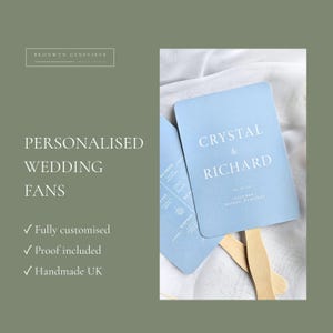 May include: Light blue rectangular wedding fans with rounded corners and wooden handles. The text reads Crystal & Richard, 03.23.25, Tolemar Nassau, Bahamas. The fans feature white serif typography and are displayed against a soft white fabric background.