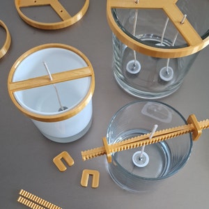 May include: A set of candle making supplies including a clear glass jar with a gold metal ring, a white glass jar with a gold metal ring, a gold metal wick holder, and a gold metal wick centering tool.