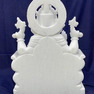 Op de afbeelding: Wit marmeren beeld van een zittende godheid met een halo en meerdere armen. Het beeld is in traditionele stijl gesneden en heeft een gedetailleerd ontwerp.