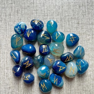 May include: A collection of blue and green agate stones with gold runes inscribed on them.