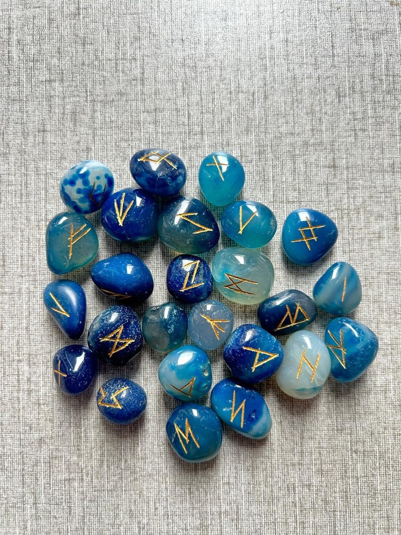 May include: A collection of blue and green agate stones with gold runes inscribed on them.