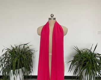 May include: A bright pink chiffon scarf draped over a mannequin. The scarf is long and flowing, and the fabric is soft and delicate.