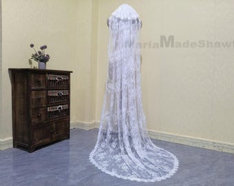 May include: A white lace wedding veil with a scalloped edge and floral pattern. The veil is long and flowing, and it is displayed on a mannequin.