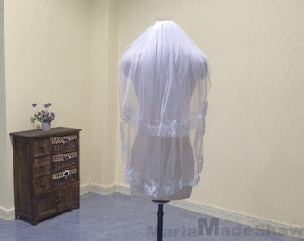 May include: A white bridal veil with a single layer of lace trim. The veil is displayed on a mannequin.