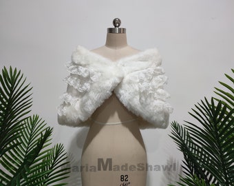 May include: White faux fur shawl with a lace trim. The shawl is draped over a dress form.