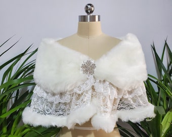 May include: White faux fur shawl with a lace trim and a rhinestone brooch.