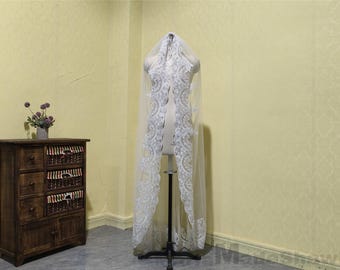 May include: A white bridal veil with delicate lace trim and a scalloped edge. The veil is displayed on a mannequin and is made of soft, sheer fabric.
