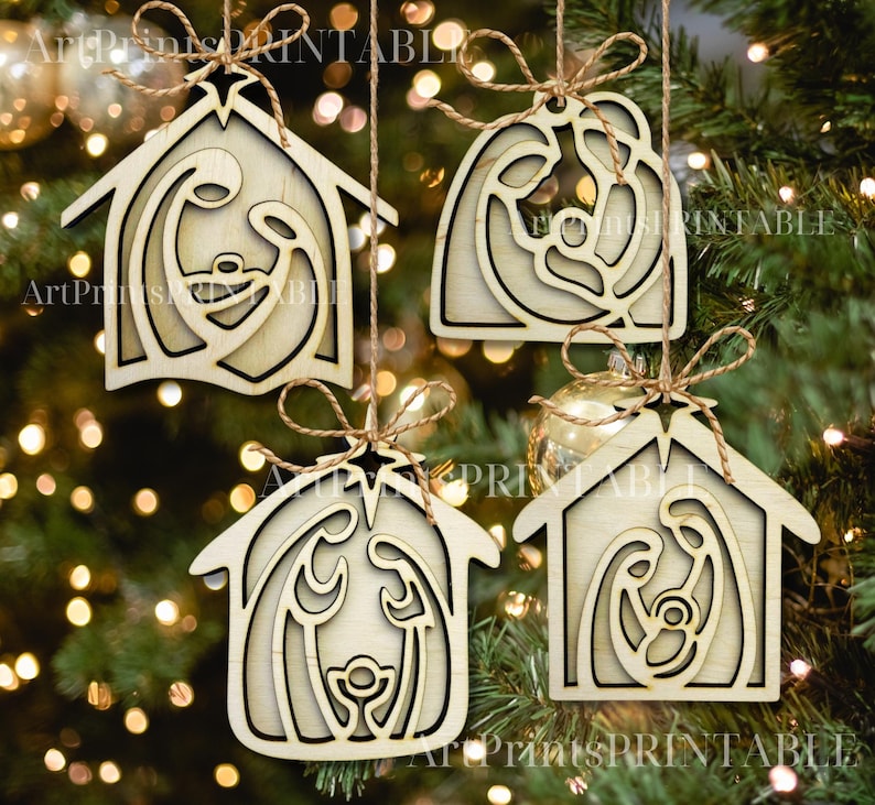 May include: Four wooden Christmas ornaments depicting the Nativity scene, hanging from twine. The ornaments are in the shape of a house or a rounded shape, with a star at the top. The ornaments are made of light-colored wood.