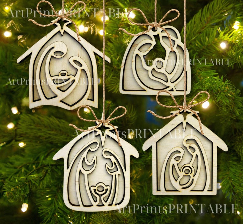 May include: Four wooden Christmas ornaments depicting the Nativity scene, hanging from twine. Each ornament is a light-colored wooden cutout of a house shape or a curved shape, with the Nativity figures inside. The ornaments are hanging on a Christmas tree.