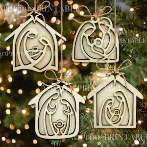 May include: Four wooden Christmas ornaments depicting the Nativity scene, hanging from twine. The ornaments are in the shape of a house or a rounded shape, with a star at the top. The ornaments are made of light-colored wood.