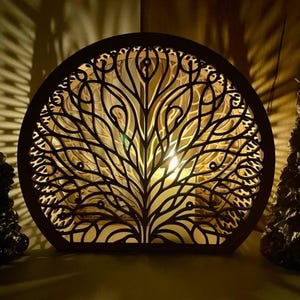 May include: A decorative, round wooden lamp with a tree of life design. The lamp is made of dark brown wood and has intricate cut-out patterns that allow light to shine through. The lamp is illuminated from within, creating a warm glow.