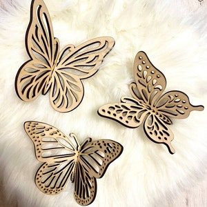 May include: Three wooden butterfly wall decor pieces in a light brown color. The butterflies are intricately cut with a delicate design and have a natural wood finish.