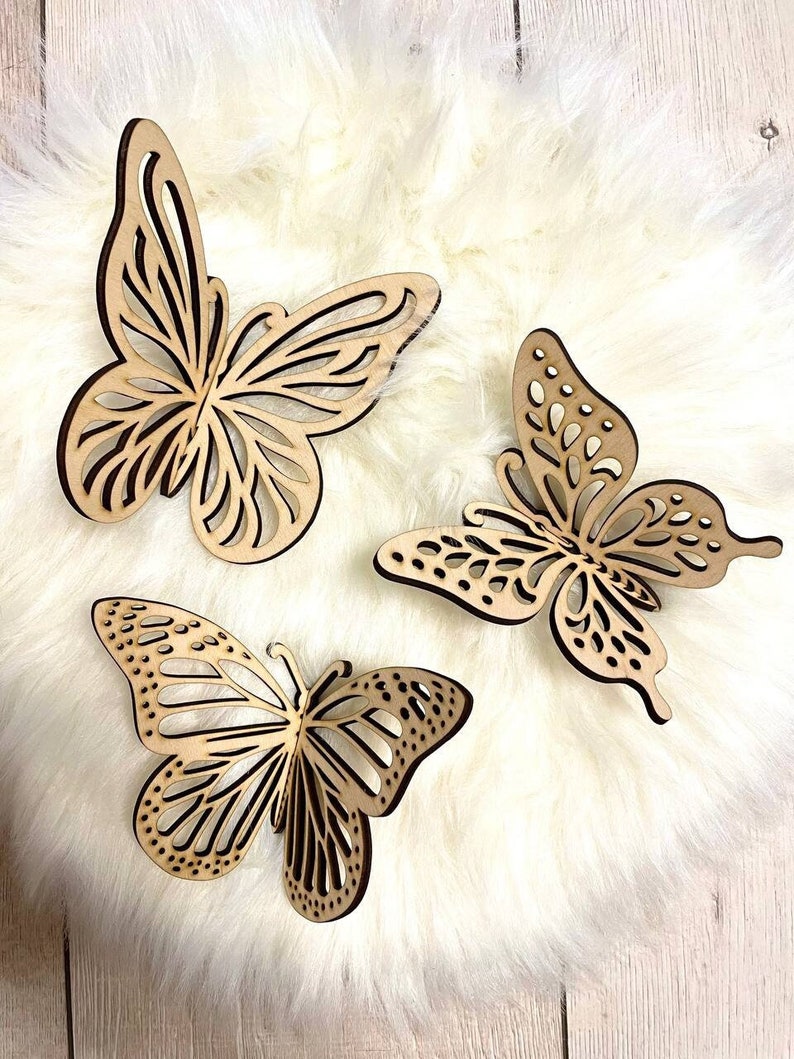 May include: Three wooden butterfly wall decor pieces in a light brown color. The butterflies are intricately cut with a delicate design and have a natural wood finish.