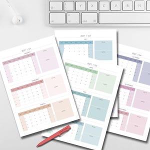 May include: A collection of pastel-colored 2021 monthly calendar pages. Each page features a month's calendar, a notes section, and a view section. A red pen and a white keyboard are also visible.