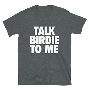 May include: Dark heather gray t-shirt with the text "TALK BIRDIE TO ME" in bold white letters. The shirt has short sleeves and a crew neck. A casual tee for everyday wear.