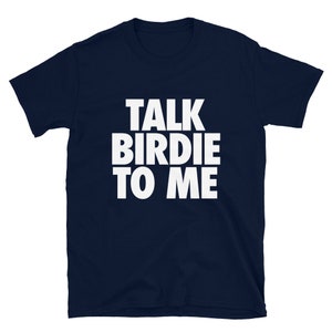May include: Navy blue t-shirt with the white text "TALK BIRDIE TO ME" in a bold, sans-serif font. The shirt is a short-sleeved crew neck, likely made of cotton or a similar fabric. The text is centered on the chest.