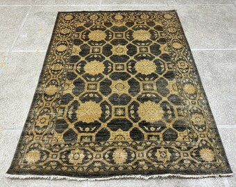 Puede incluir: Una alfombra marrón oscuro con un patrón geométrico en un color marrón más claro. La alfombra tiene un borde con flecos.