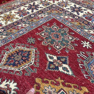 May include: A red, blue, and green patterned rug with intricate designs. The rug has a traditional Persian style and is made of wool.