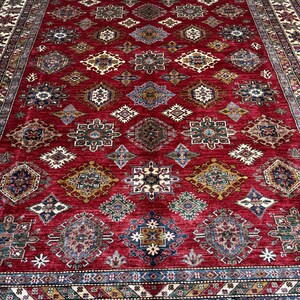 May include: A red, blue, and beige patterned rug with a geometric design. The rug has a central medallion and a border with intricate details.
