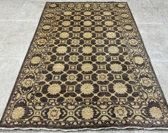 Puede incluir: Una alfombra de área marrón y beige con un patrón geométrico. La alfombra tiene un borde detallado con un diseño repetitivo.